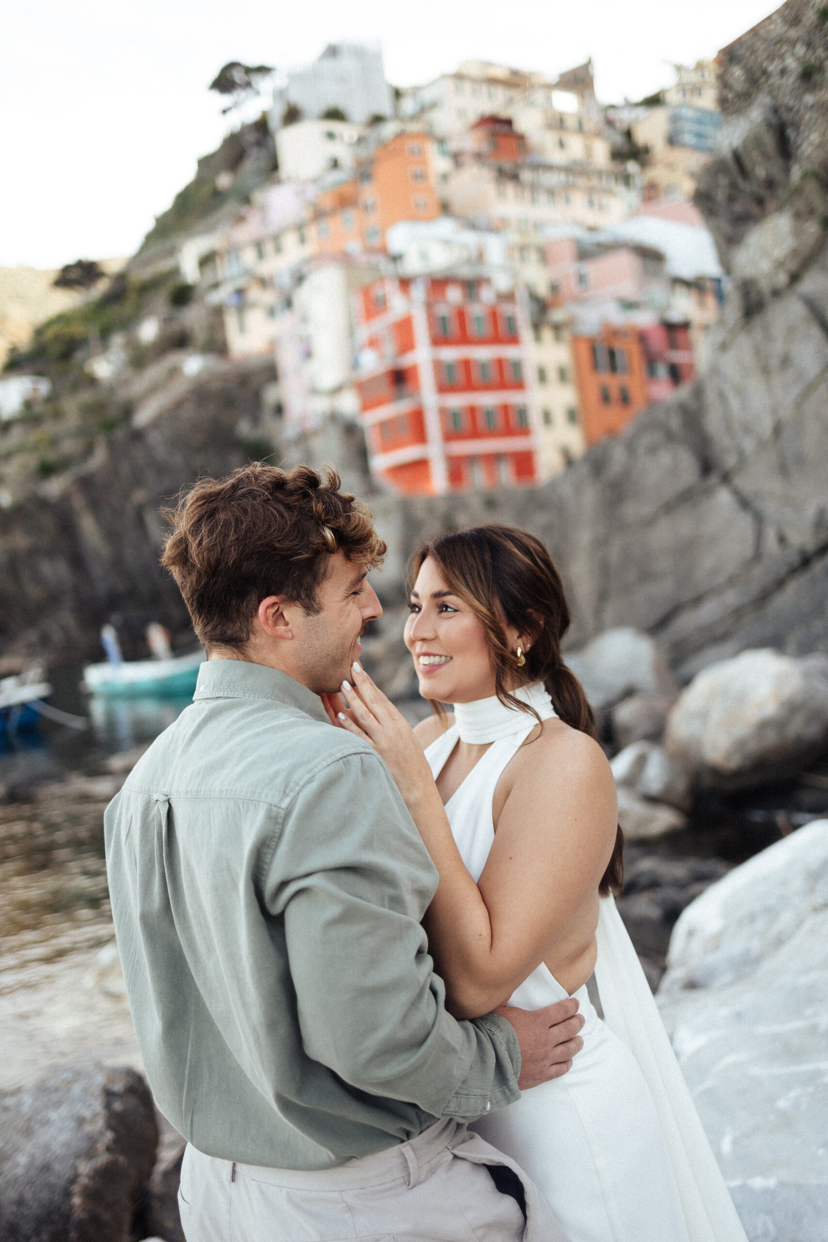 A couple who eloped in Cinque Terre. Standing before on of the coast towns of Italy, Riomaggiore.